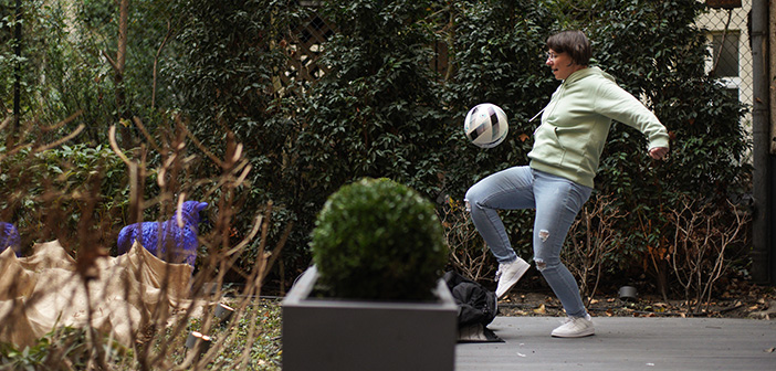 Eine Frau spielt in einem Garten Fußball