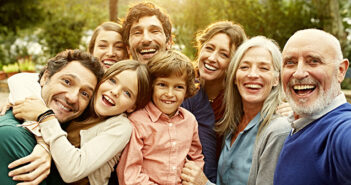 Eine glückliche Familie in drei Generationen schaut lachend in die Kamera.