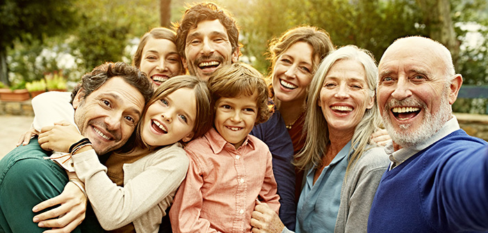 Eine glückliche Familie in drei Generationen schaut lachend in die Kamera.