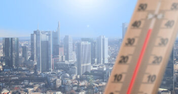 Bildmontage: ein Thermometer im Vordergrund zeigt knapp 40 Grad an, während im Hintergrund eine Großstadt mit Skyline aus der Vogelperspektive zu sehen ist.